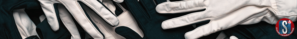 White and black fabric work gloves stacked on a dark surface, representing Skookum Tools’ fabric safety gloves for light-duty, assembly, and general work applications.